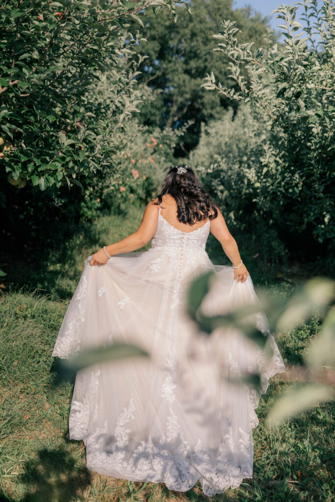 a young, natural bride walking through an orchard in a beautiful white wedding dress